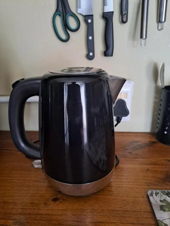Black electric kettle on wooden kitchen counter with utensils