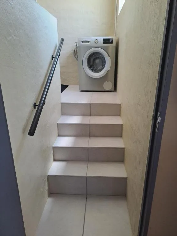 Modern washing machine in compact utility room with stairs