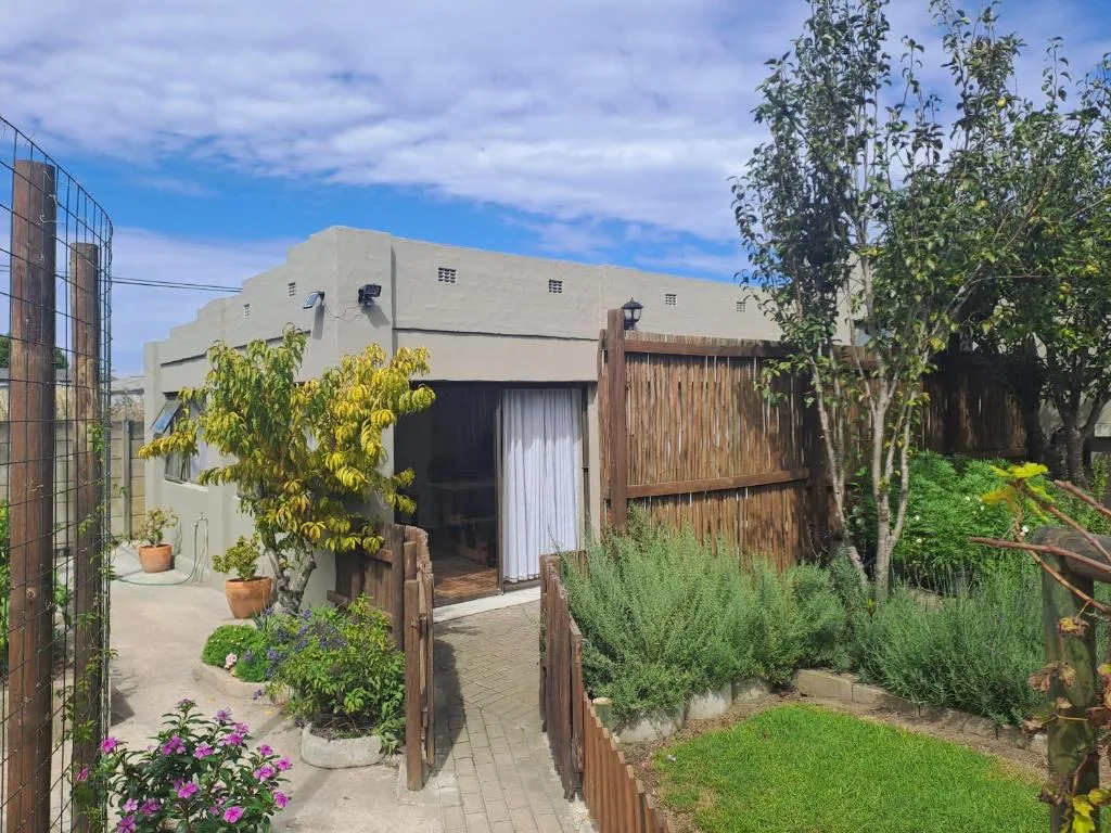 Modern beige apartment entrance with manicured gardens and wooden gates