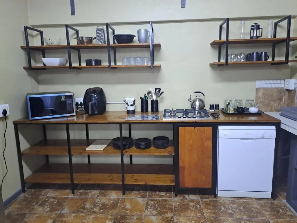 Modern kitchen with open shelving, gas cooktop, microwave, and dishwasher