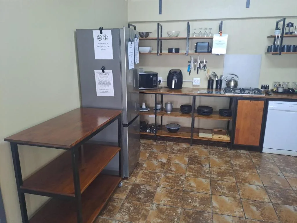 Modern kitchen with stainless steel appliances, wooden counter, and open shelving