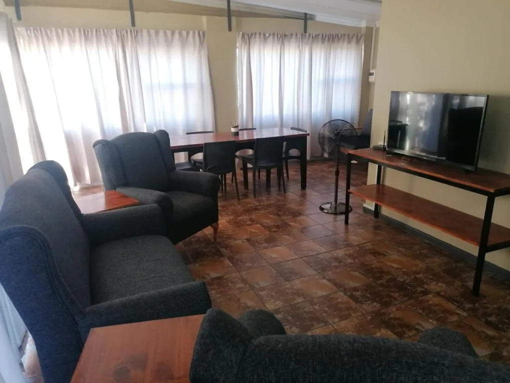 Spacious lounge with comfortable seating, TV, and natural light from windows