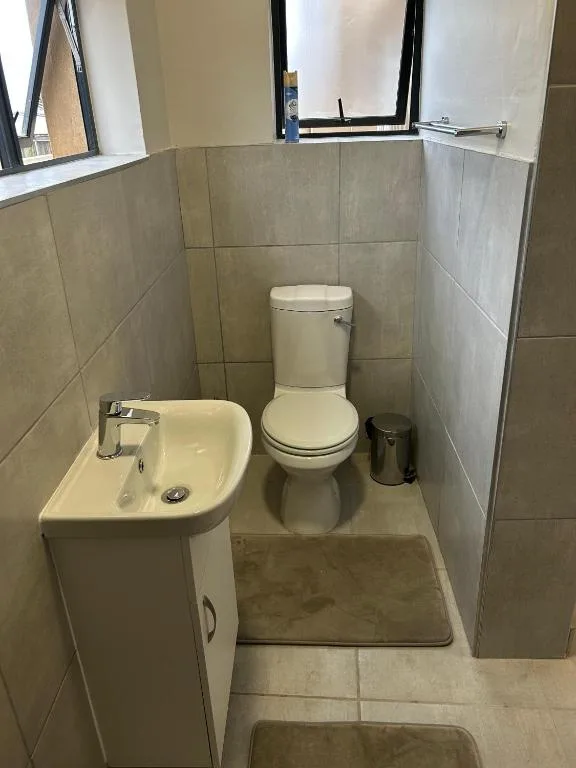 Compact bathroom with toilet, sink, and tiled walls, small window above