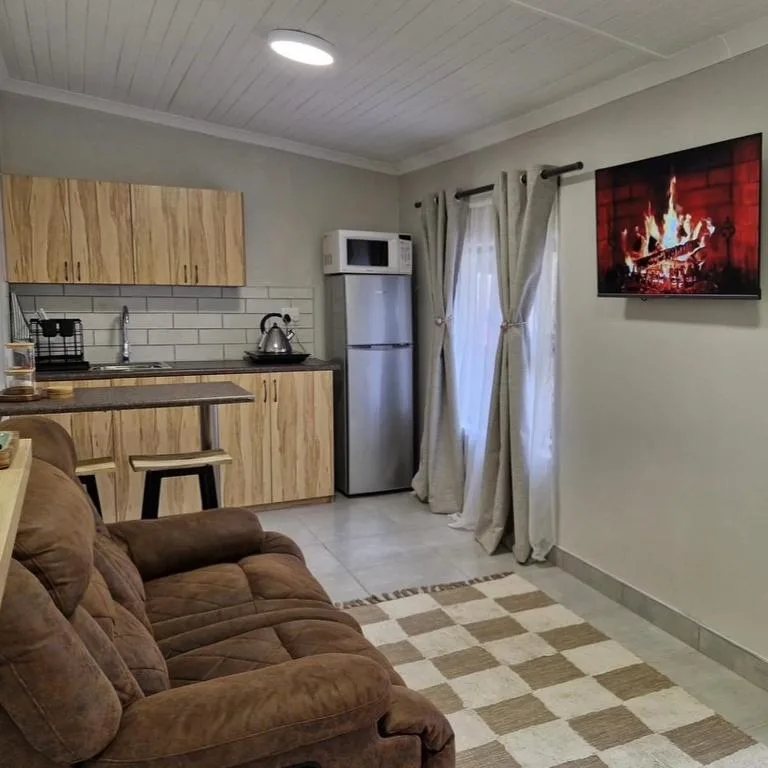 Open-plan lounge and kitchen with brown sofa and modern appliances