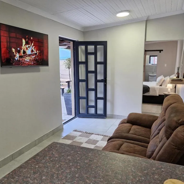 Open-plan lounge with brown armchair, TV, and ocean view through glass doors