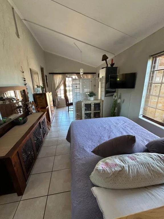 Spacious bedroom with blue-covered bed, wooden furniture, and open-plan layout