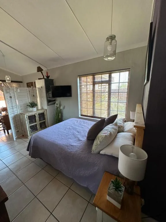 Bright bedroom with blue bedspread, wooden bed frame, and large windows