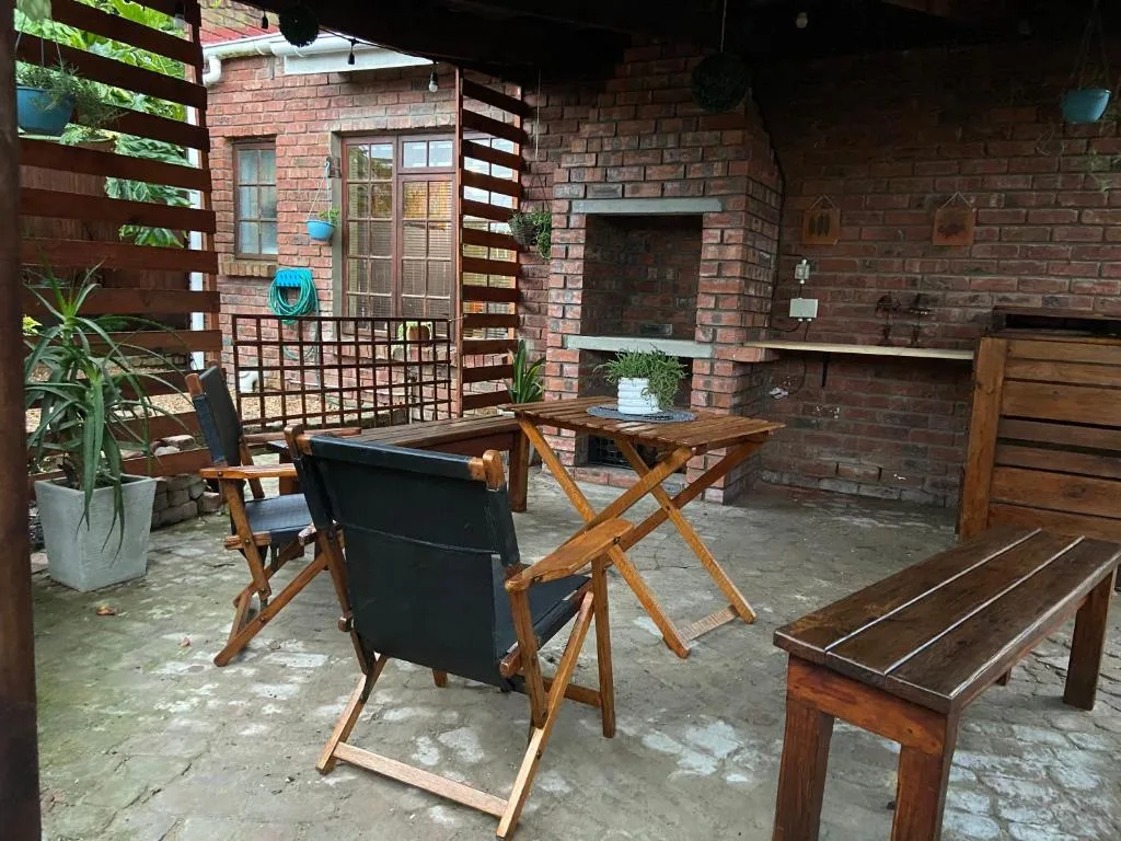 Outdoor patio with wooden furniture, fireplace, and brick walls