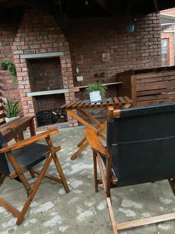 Outdoor patio with wooden chairs and brick fireplace backdrop