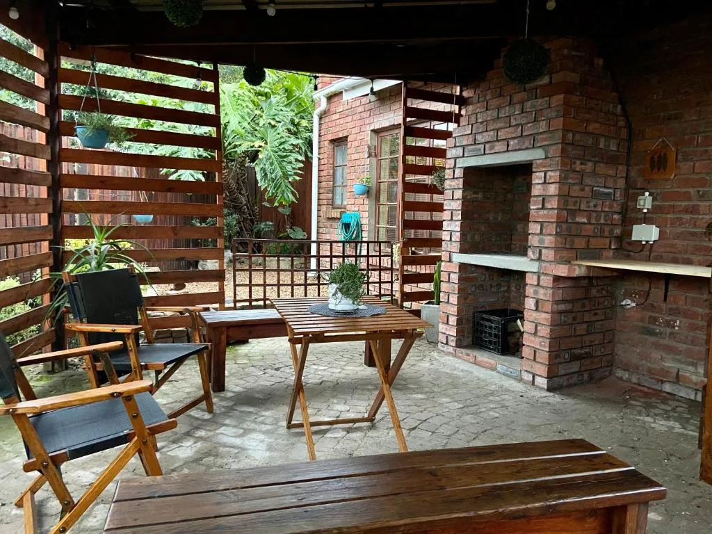 Covered patio with wooden furniture, brick fireplace, and lush greenery