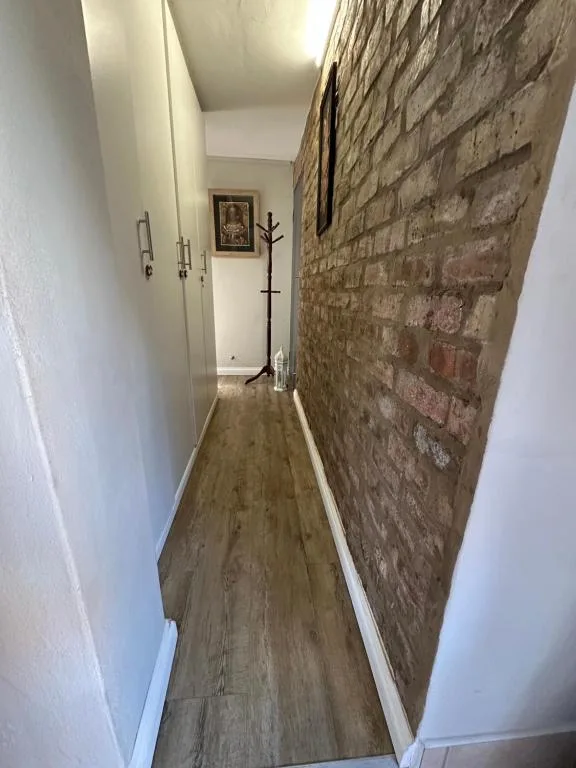 Narrow hallway with exposed brick wall and wooden flooring