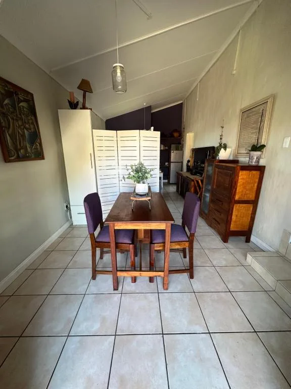 Wooden dining table with purple chairs in bright, airy room