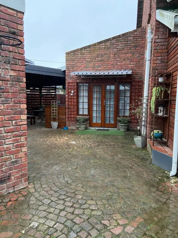 Brick cottage entrance with wooden French doors and courtyard paving