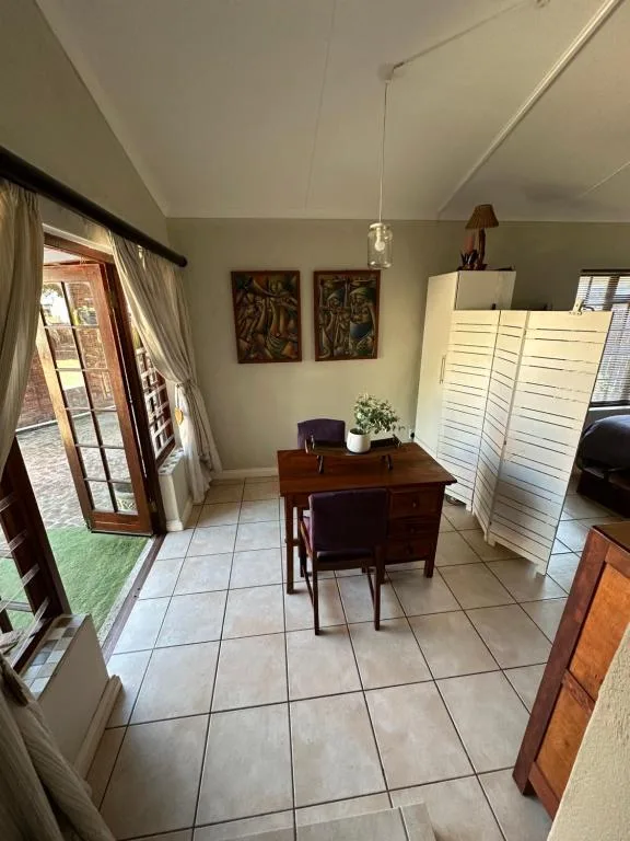 Bright lounge area with wooden desk, comfortable seating, and garden access