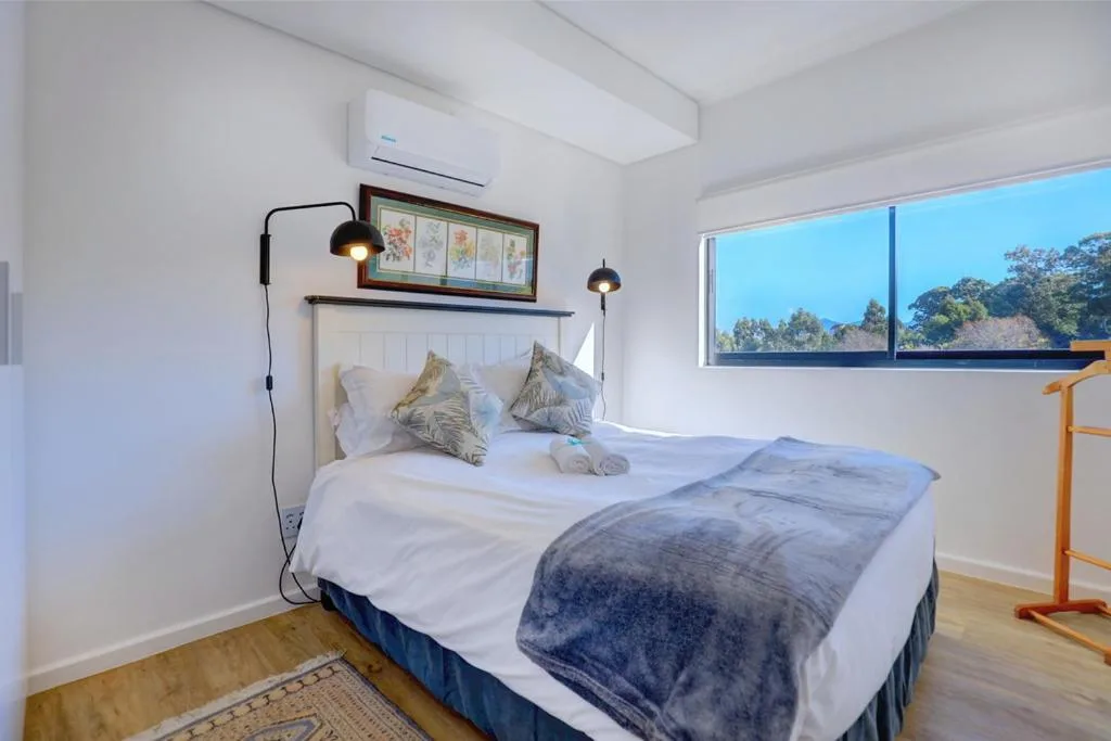 Bright bedroom with queen bed, wall sconces, and mountain view through window