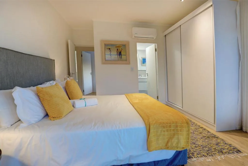 Bright bedroom with queen bed, yellow cushions, and sliding wardrobe doors