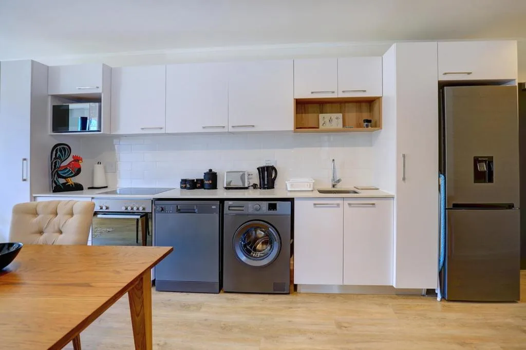 Modern kitchen with white cabinetry, stainless steel appliances, and wooden countertops