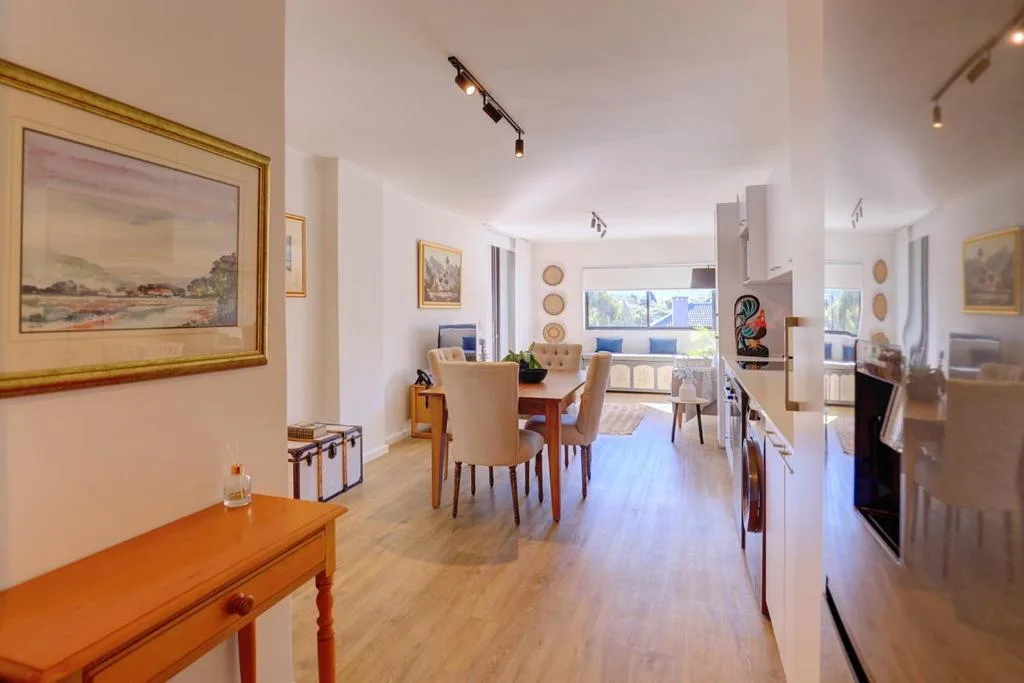 Open-plan living area with dining table, lounge seating, and kitchen appliances visible