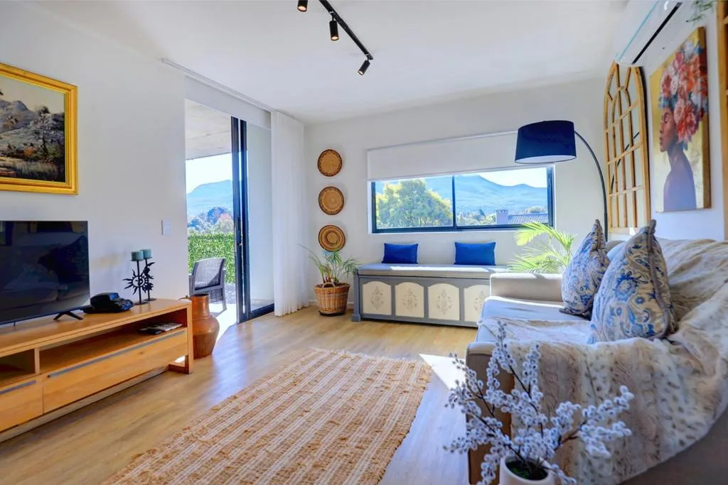 Bright open-plan lounge with sofa, TV, mountain views through large windows