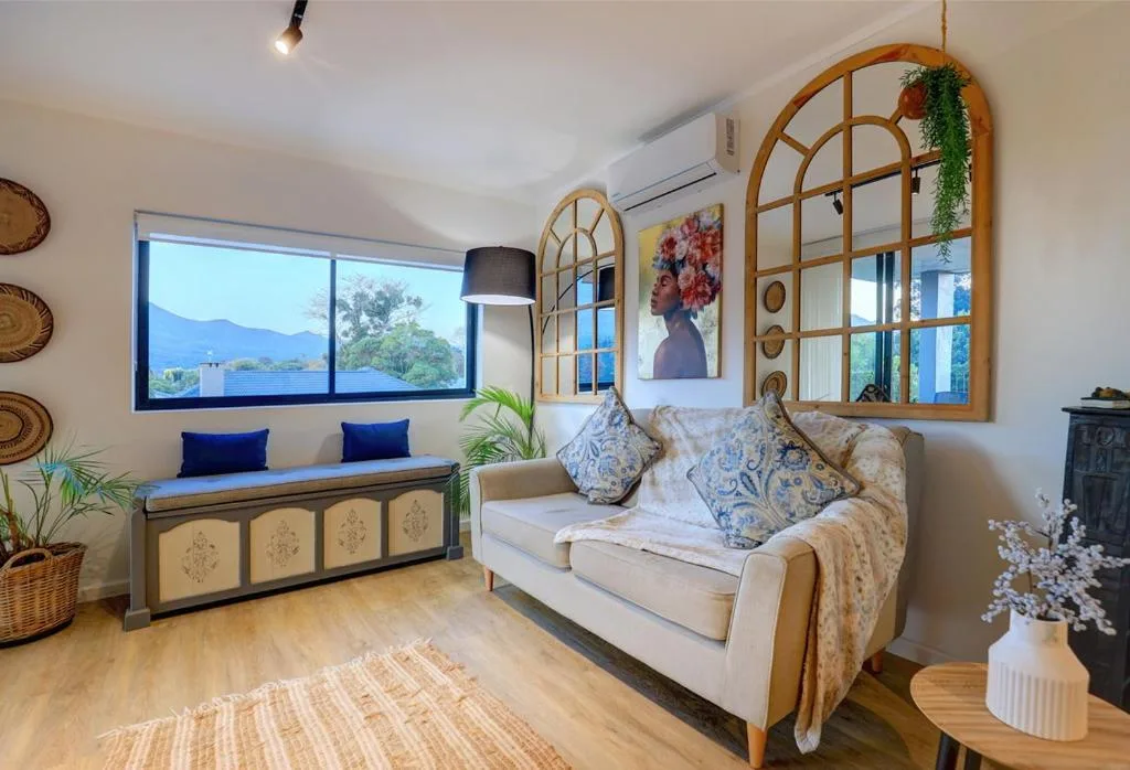 Bright lounge with cream sofa, mountain views through large windows, decorative mirrors