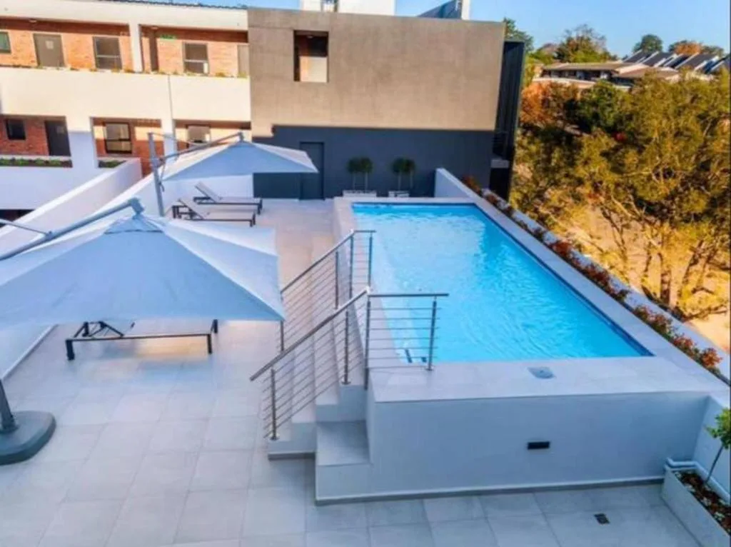 Modern rectangular swimming pool with loungers and surrounding paved deck area