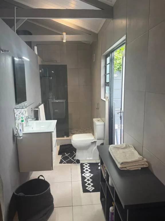 Modern bathroom with shower, toilet, vanity sink, and window access