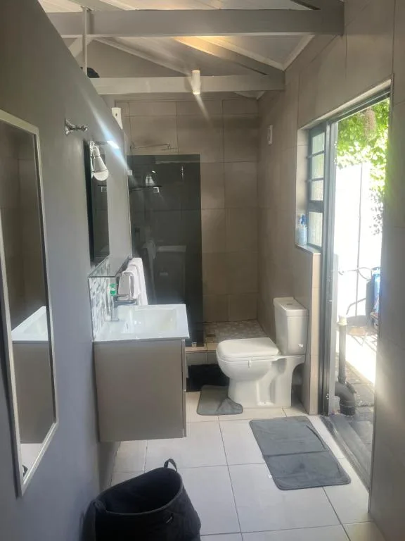 Modern bathroom with black shower, vanity sink, toilet, and bright skylight