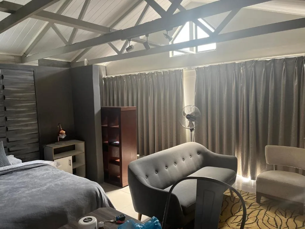 Modern bedroom with bed, seating area, and exposed beam ceiling