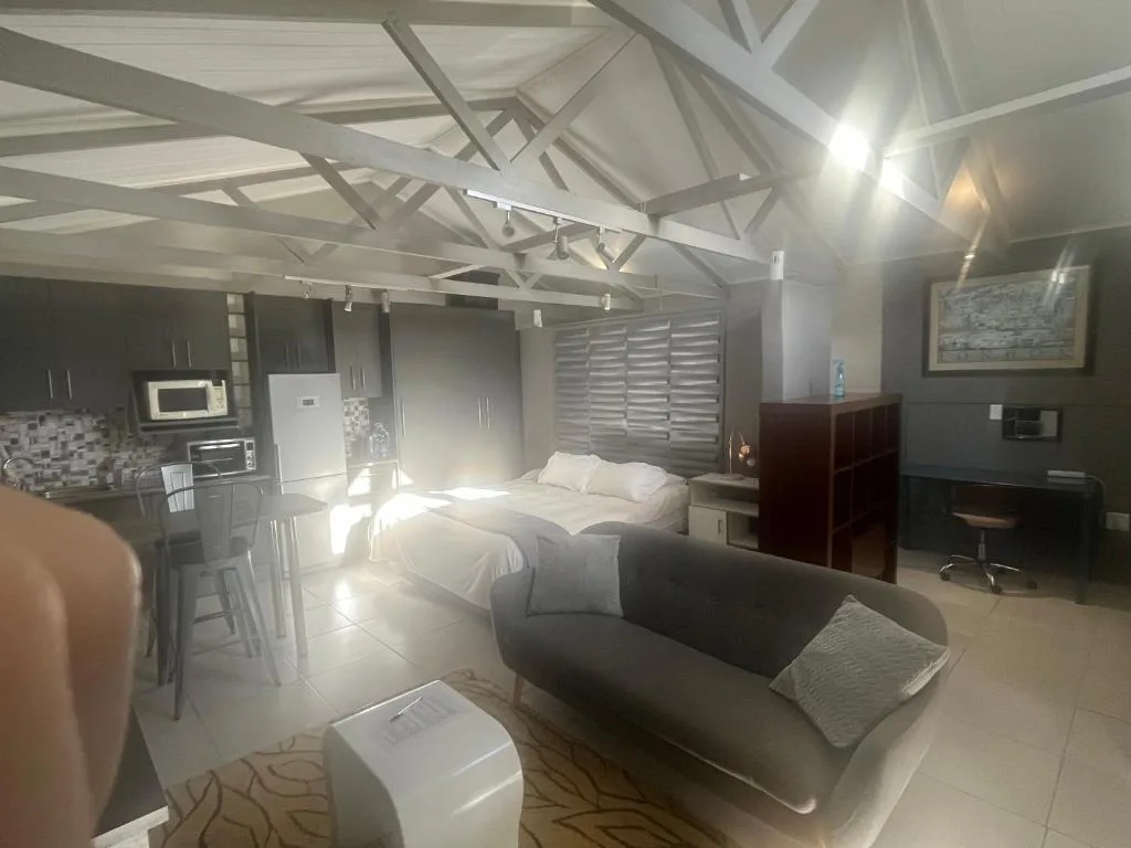 Modern studio bedroom with bed, lounge seating, and open-plan kitchen area