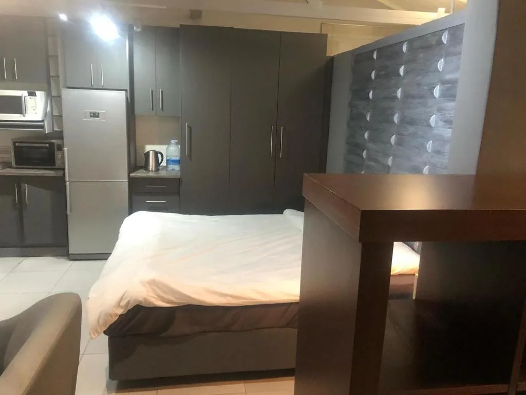 Modern studio bedroom with double bed and integrated kitchen area visible