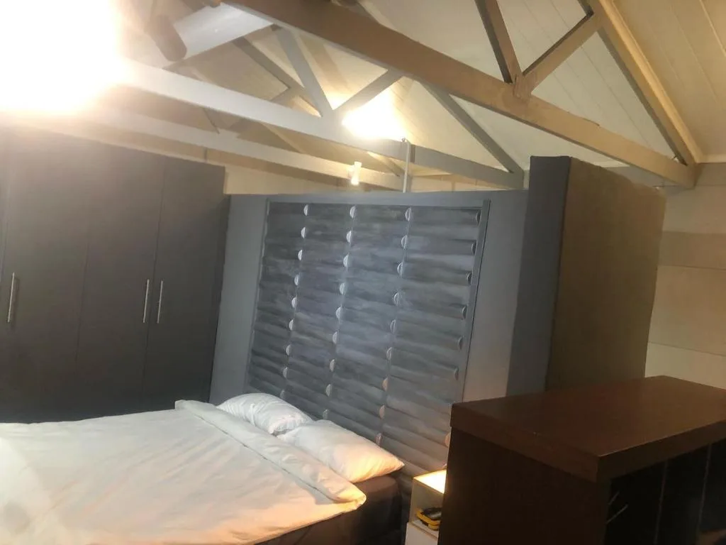 Spacious bedroom with bed, modern headboard, and exposed beam ceiling