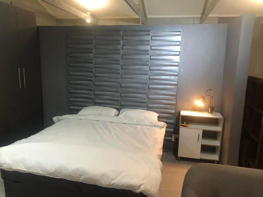 Modern bedroom with queen bed, grey headboard, and bedside table with lamp