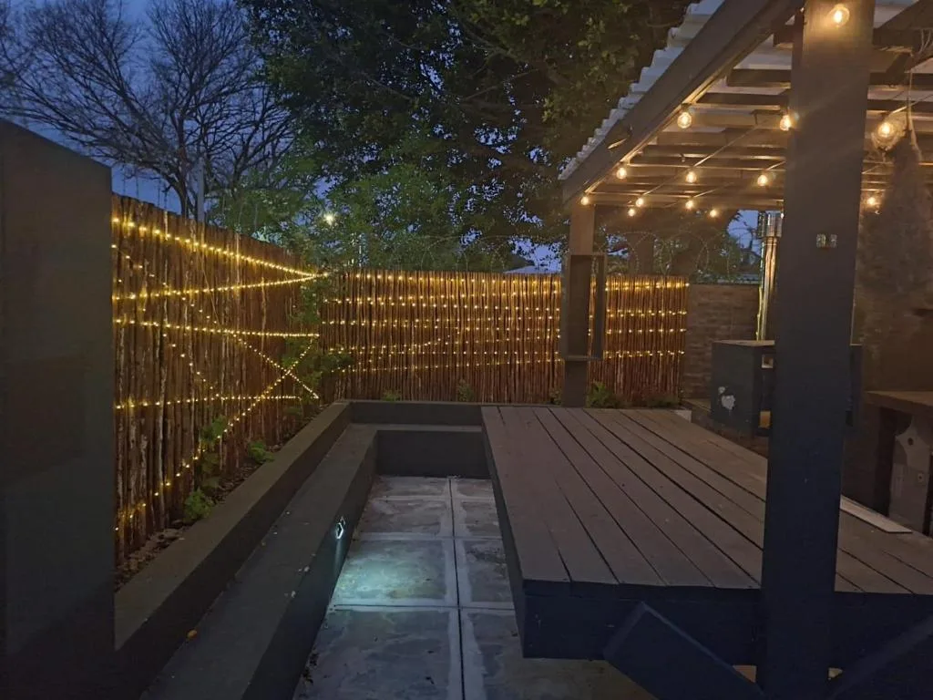 Illuminated deck with wooden flooring and string lights at dusk