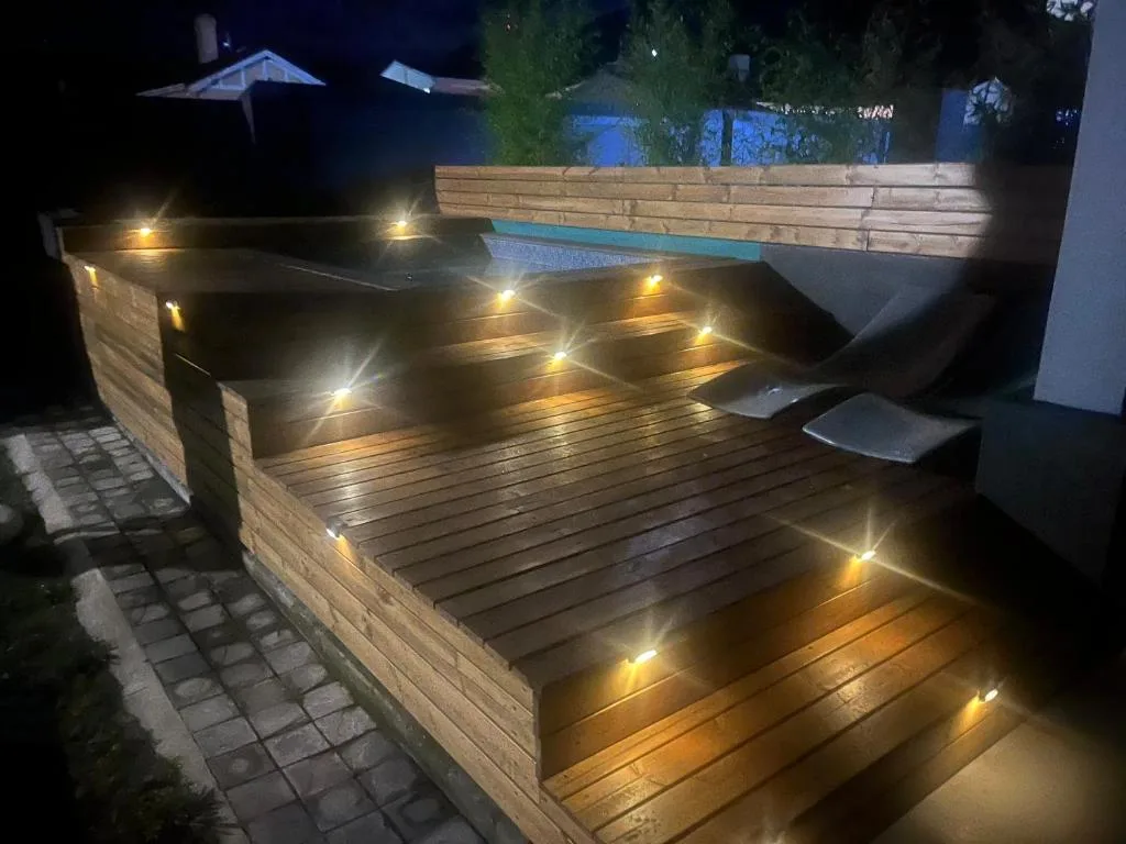 Illuminated wooden deck with warm LED lighting and comfortable seating area at night