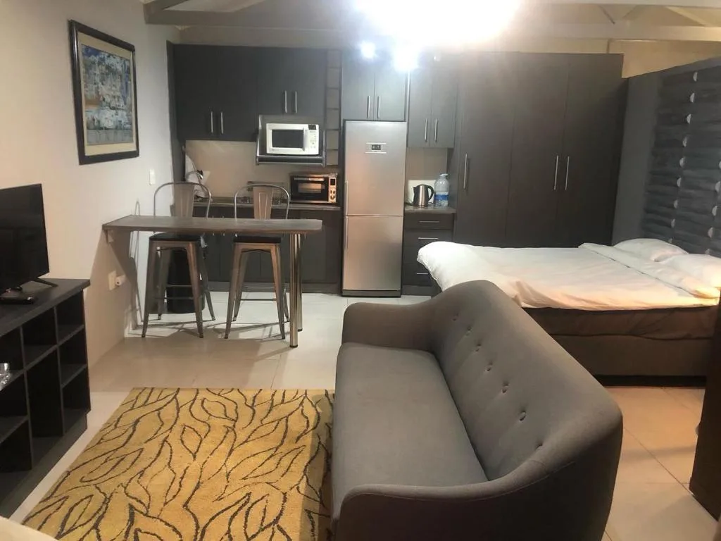 Modern open-plan studio with kitchen, dining area, bed, and lounge seating