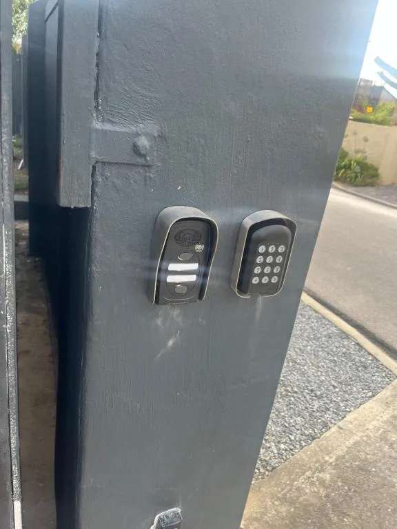 Electronic keypad and intercom system mounted on dark gate entrance