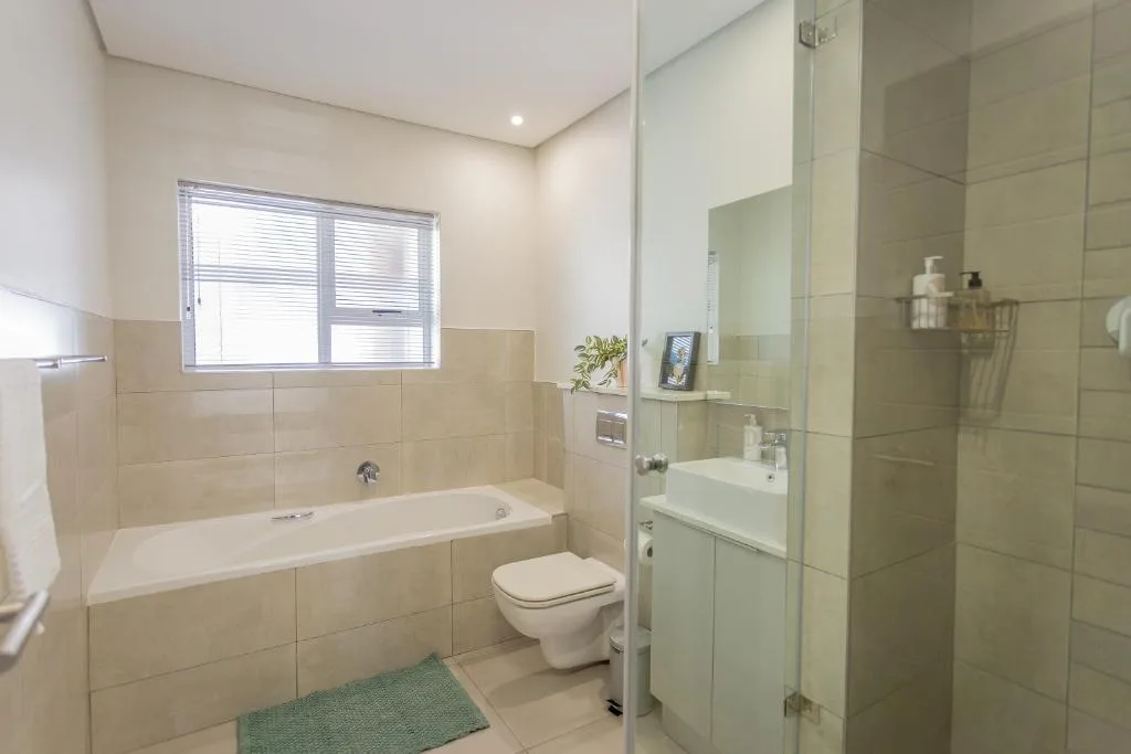 Modern bathroom with bathtub, toilet, vanity sink, and glass shower enclosure