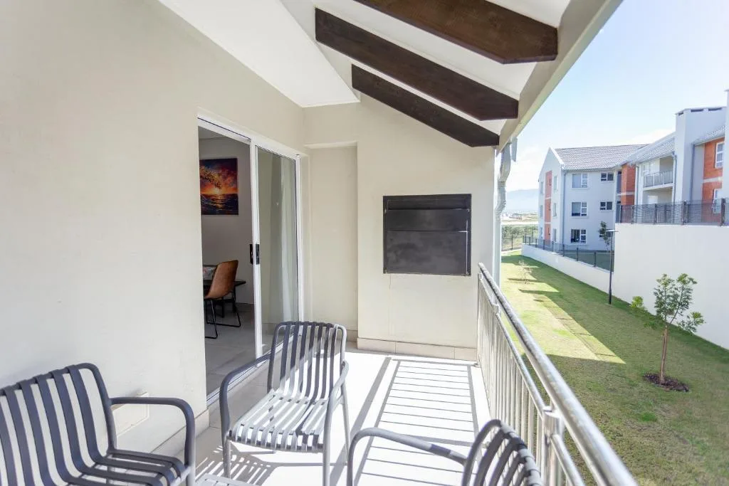 Balcony with striped chairs overlooking manicured gardens and apartment buildings