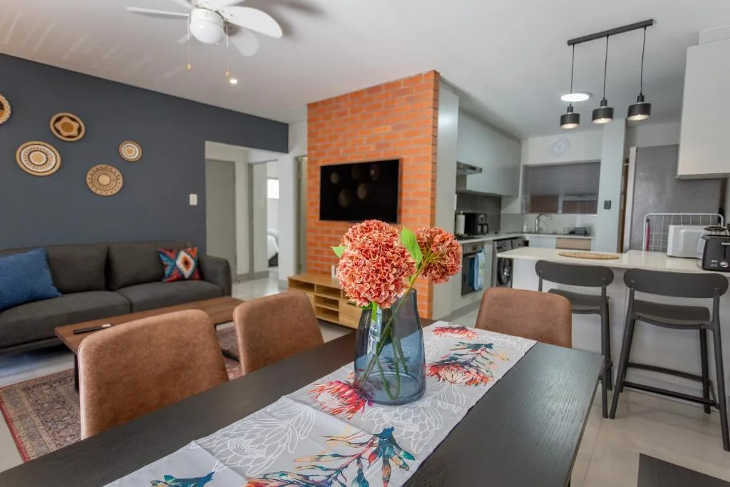 Modern dining table with fresh flowers, open-plan kitchen and lounge visible