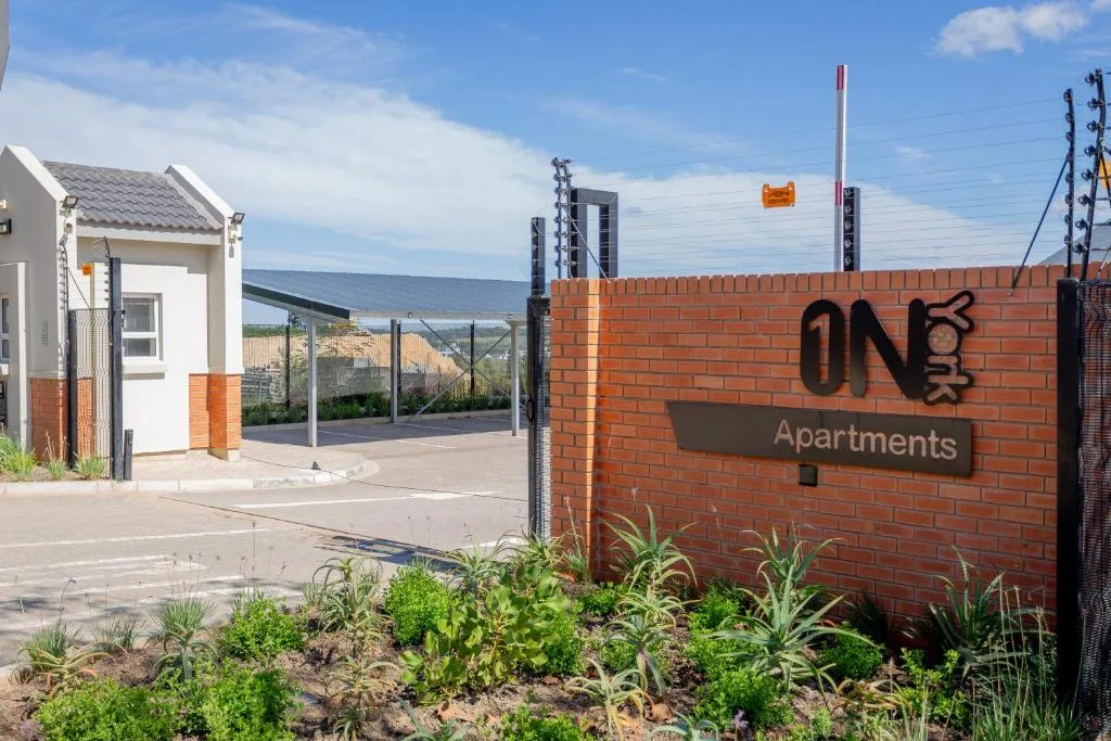 Modern apartment entrance with brick signage and landscaped gardens