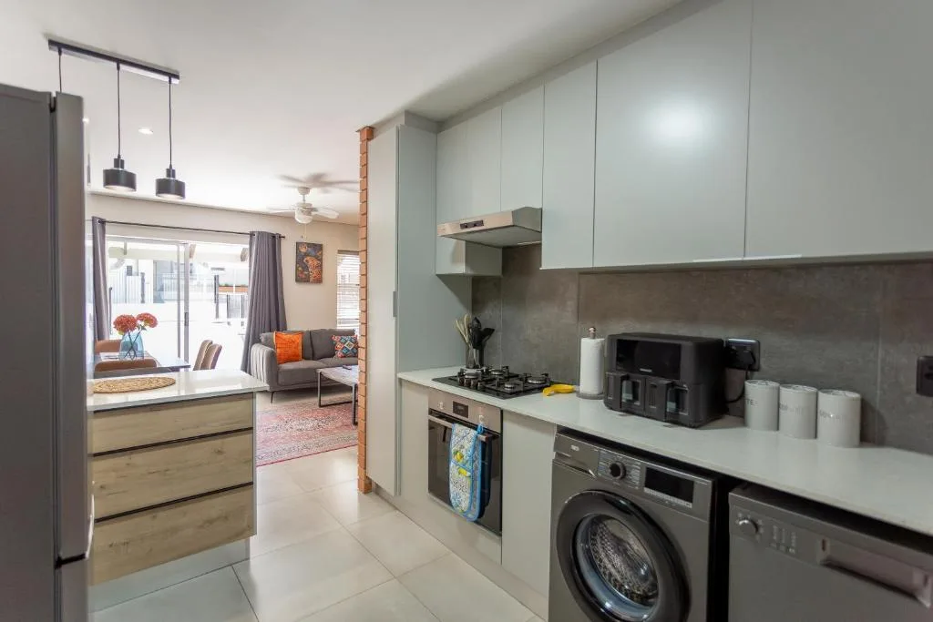 Modern kitchen with sage cabinetry, gas stove, washing machine, and pendant lights