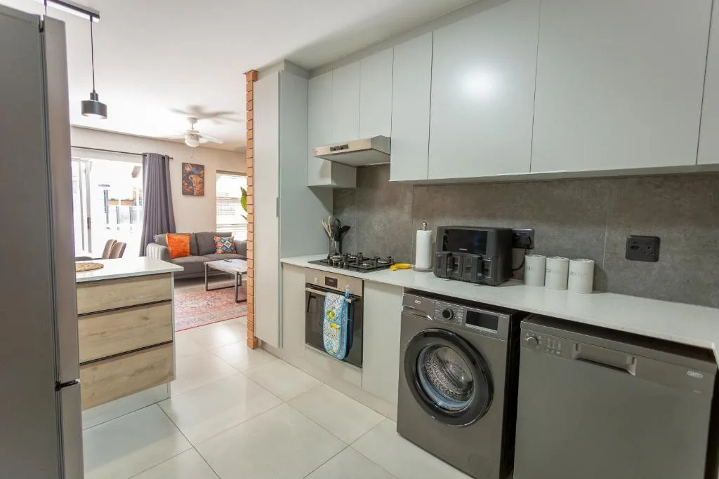 Modern kitchen with white cabinetry, gas stove, washing machine, and grey backsplash
