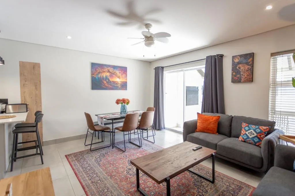 Open-plan lounge with gray sofa, dining table, and colorful artwork decor