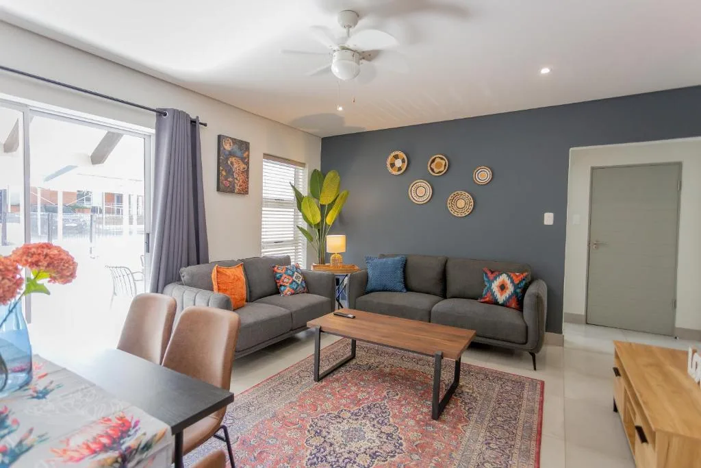 Modern lounge with gray sofa, colorful cushions, wooden coffee table, and wall art