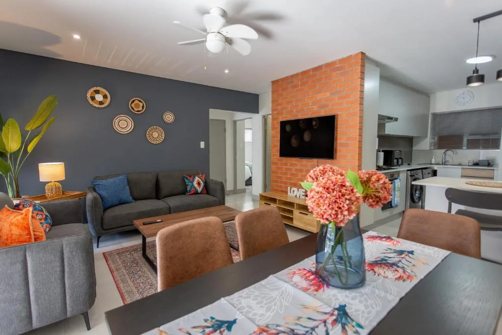 Modern open-plan lounge with gray sofa, decorative plates, and brick fireplace