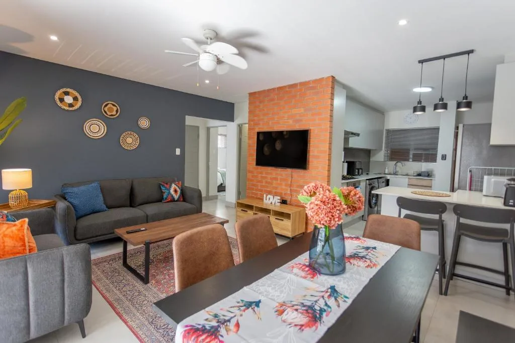 Modern living room with gray sofa, dining table, and brick fireplace accent