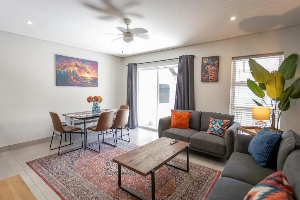 Modern lounge with gray sofa, colorful pillows, and dining area visible