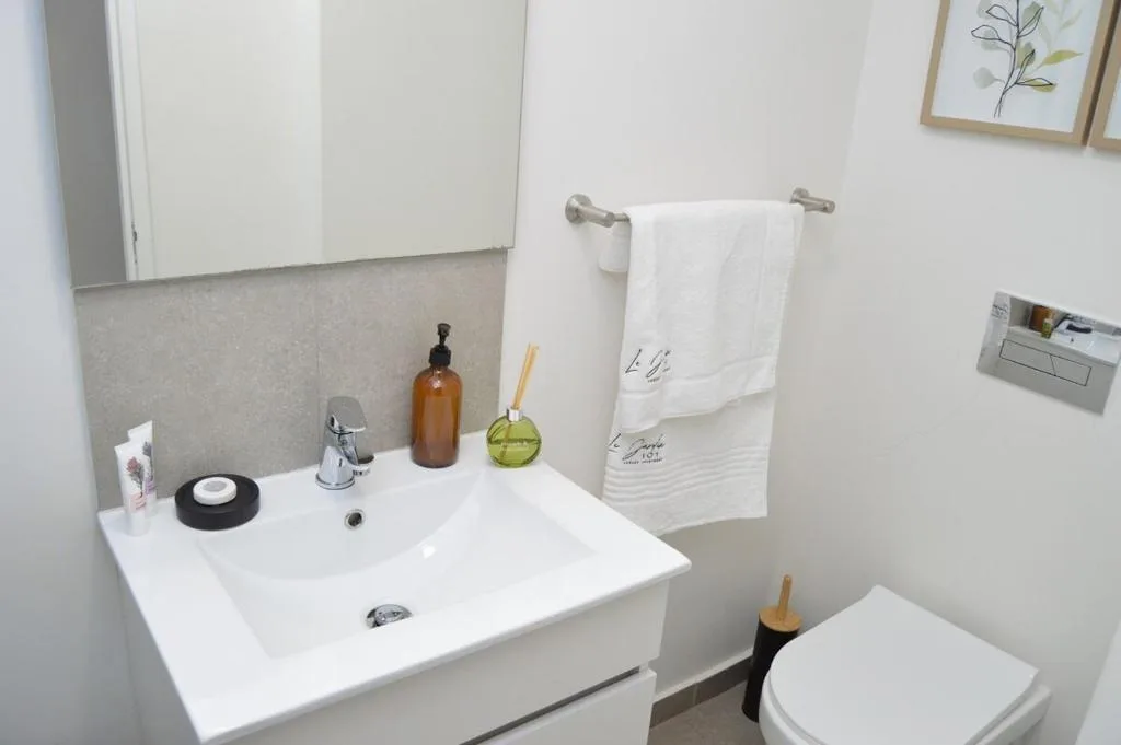 Modern bathroom with white double sink, chrome fixtures, and toiletries