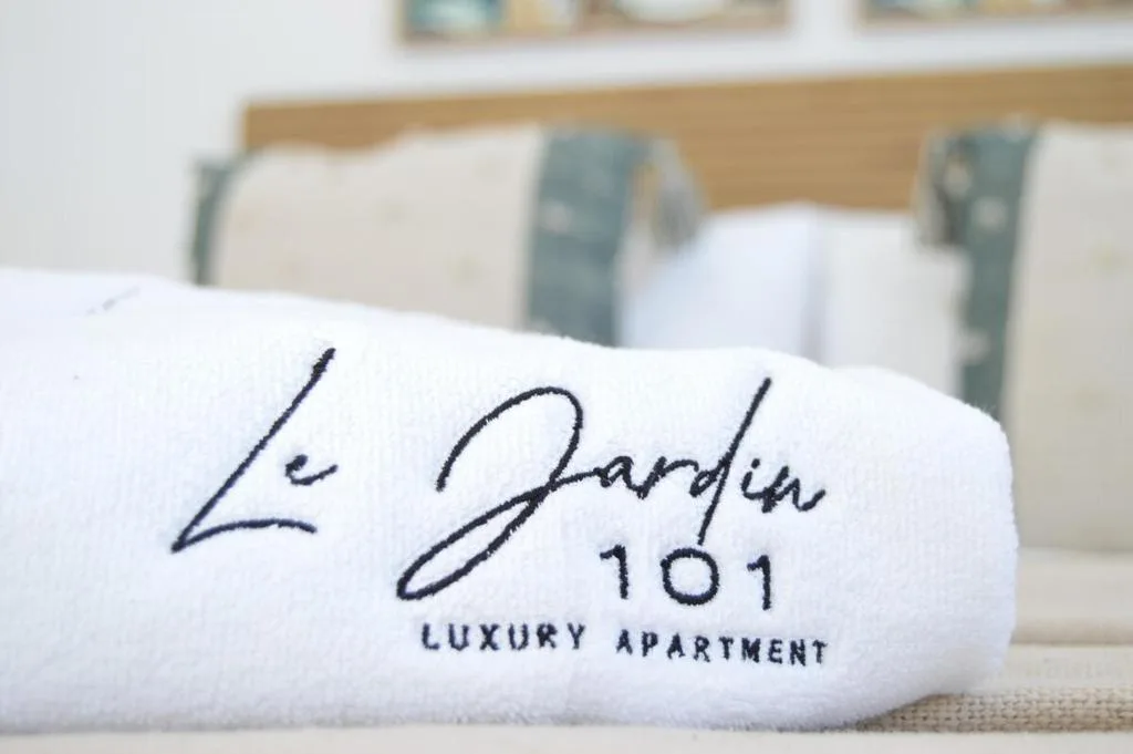 Rolled white towel embroidered with Le Jardin 101 luxury apartment branding