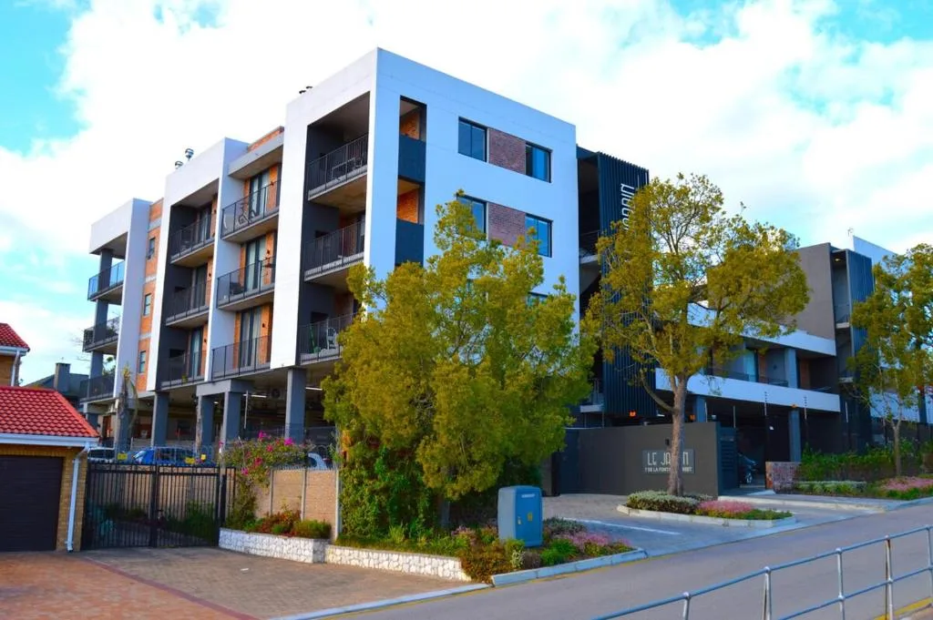Modern blue and brick apartment building with landscaped gardens and entrance